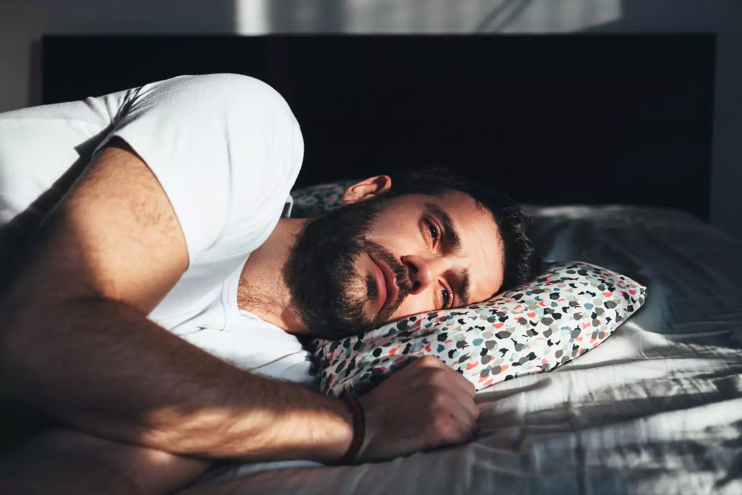 Mann liegt nachdenklich im Bett — innerer Druck und Grübeln